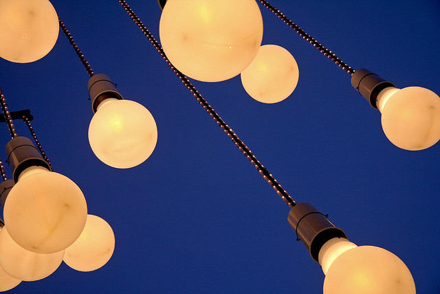 About 10 hanging light bulbs against a bright blue backdrop.
