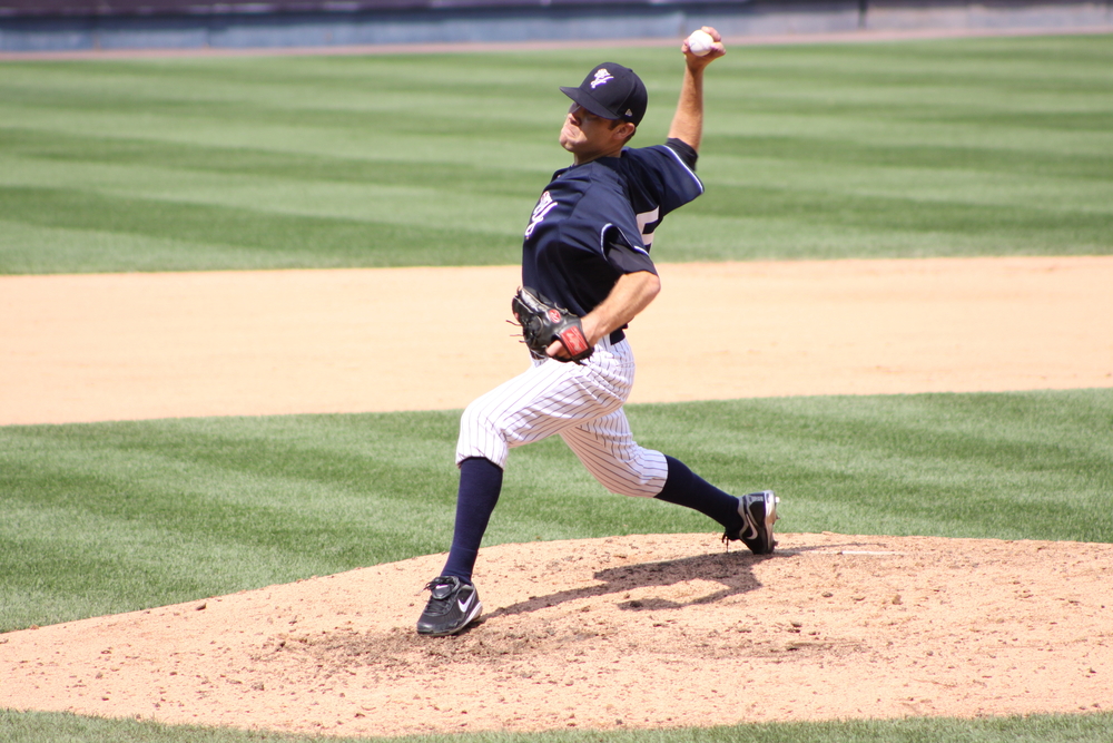 A baseball pitcher winding up for his pitch.