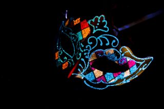 A colorful masquerade mask against a black background.