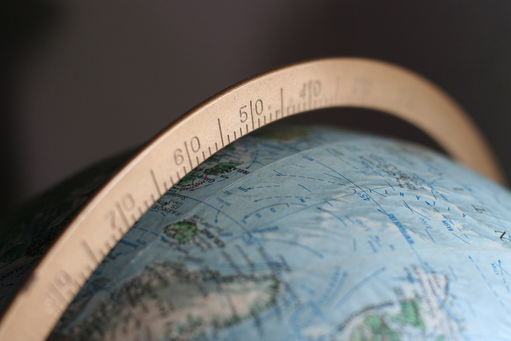 A close up of a globe and a metal meridian running around it.
