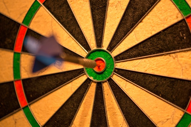 A dart board showing a single dart in the centre of the bull's eye.