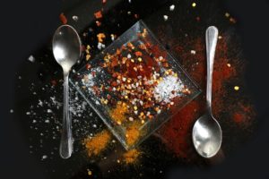 A photo of some presumably edible compounds on a square plate. There is a spoon to each side of the plate.