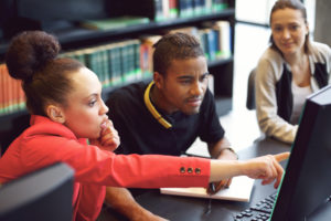 A group of three people looking at a computer screen.