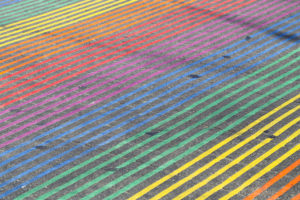 A crosswalk painted in bands of rainbow colors.