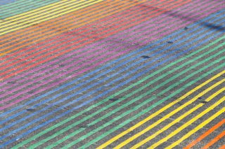 A crosswalk painted in bands of rainbow colors.