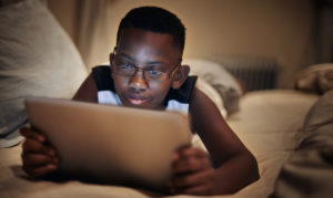 A child lying down looking at a tablet or computer.