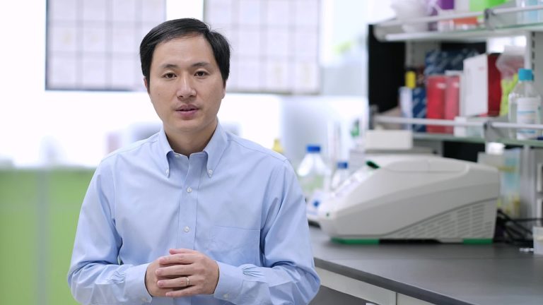 Chinese scientist He Jiankui standing in front of a laboratory bench.