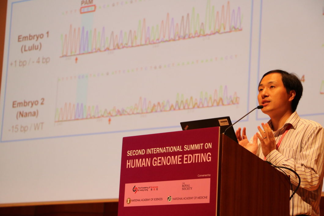 A man stands at a podium labeled Second International Summit on Human Genome Editing. Scientific data appear on a screen behind him.