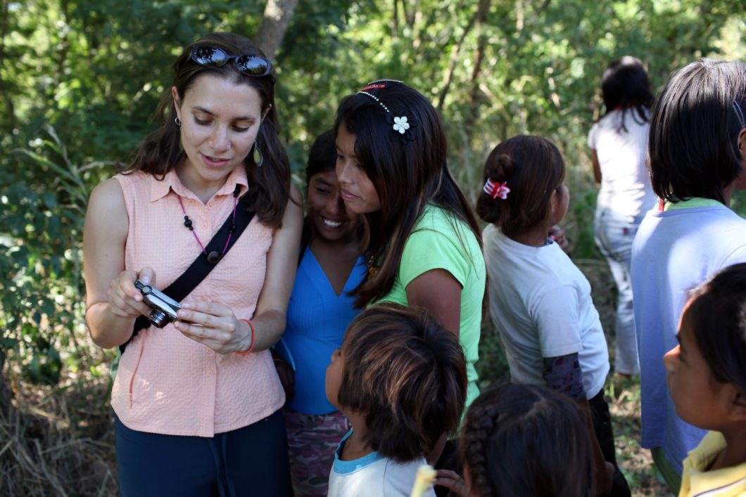 A woman showing photographs on her camera to a group of children.