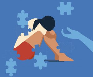 A woman sitting, arms around knees. Puzzle pieces form gaps at the edges of her body. A supportive hand reaches toward her.