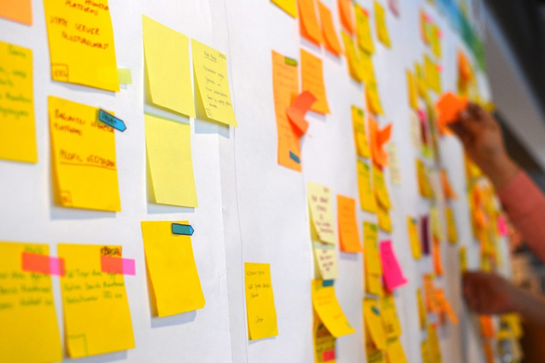 A white board covered in yellow and orange post-it notes.