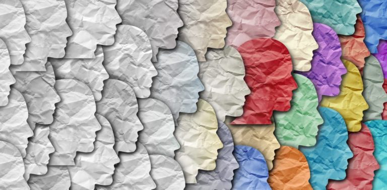 A group of faces made of tissue paper, with homogenous gray faces on the left transltioning to a diversity of colors on the right.