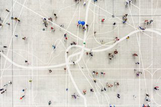 Aeriel view of a dispersed crowd standing on top of an abstract city map.