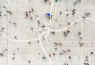 Aeriel view of a dispersed crowd standing on top of an abstract city map.