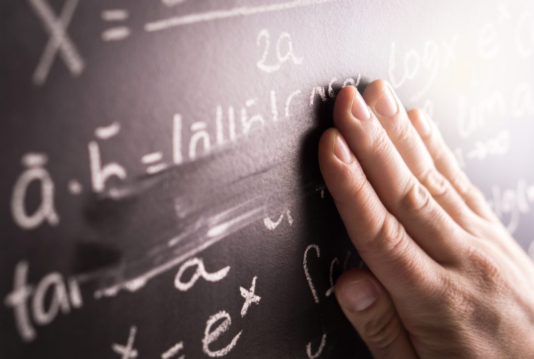 A hand erasing a mathematical formula off a blackboard.