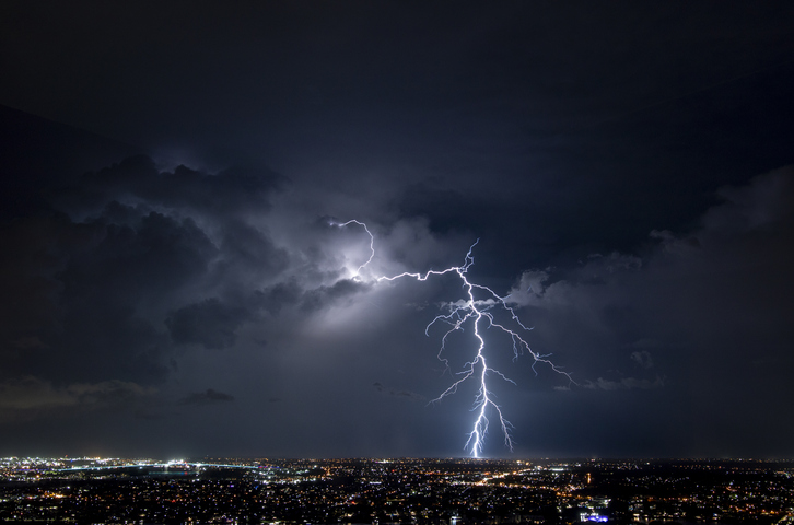 A bolt of lightning strikes in a night sky.