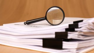 A magnifying glass rests on scattered clipped papers