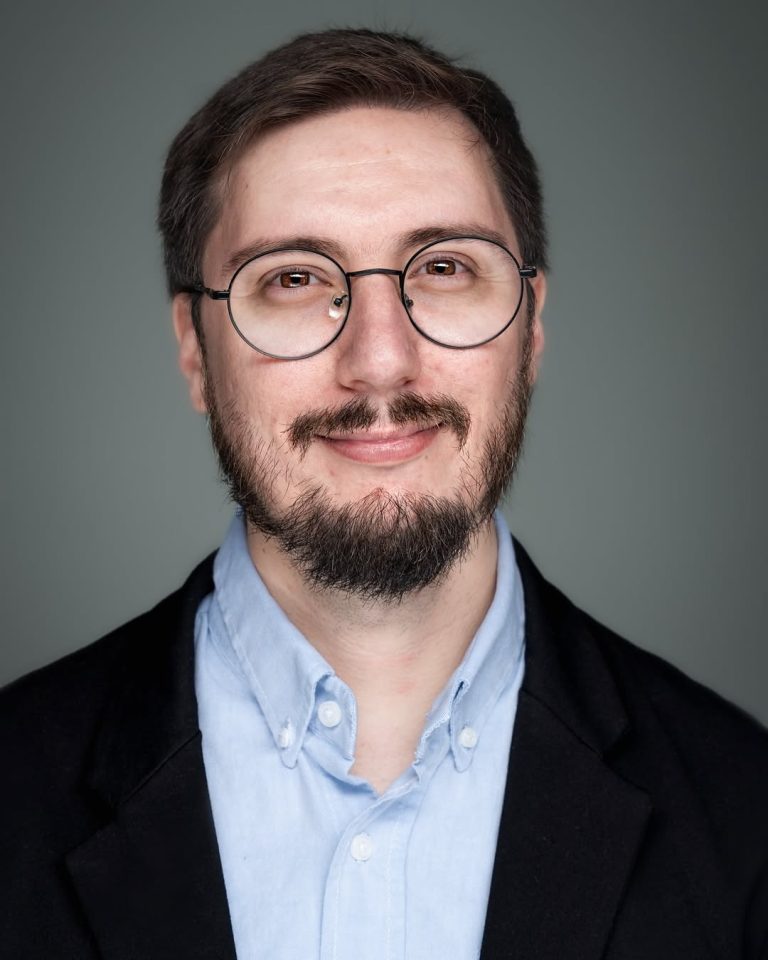 Head shot of Maximiliano Manzoni, wearing a blue shirt and a black blazer.