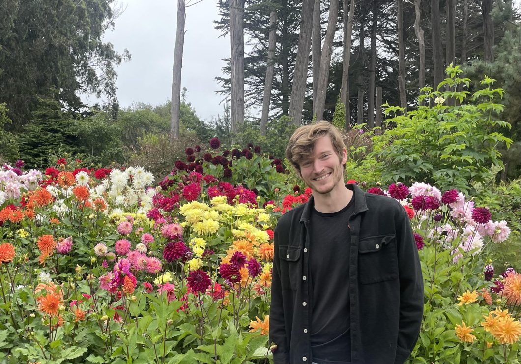 Photo of Greg Barber in front of a bed of flowers.