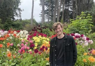 Photo of Greg Barber in front of a bed of flowers.