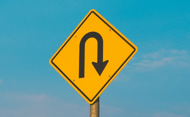 A yellow street sign indicating a U-turn